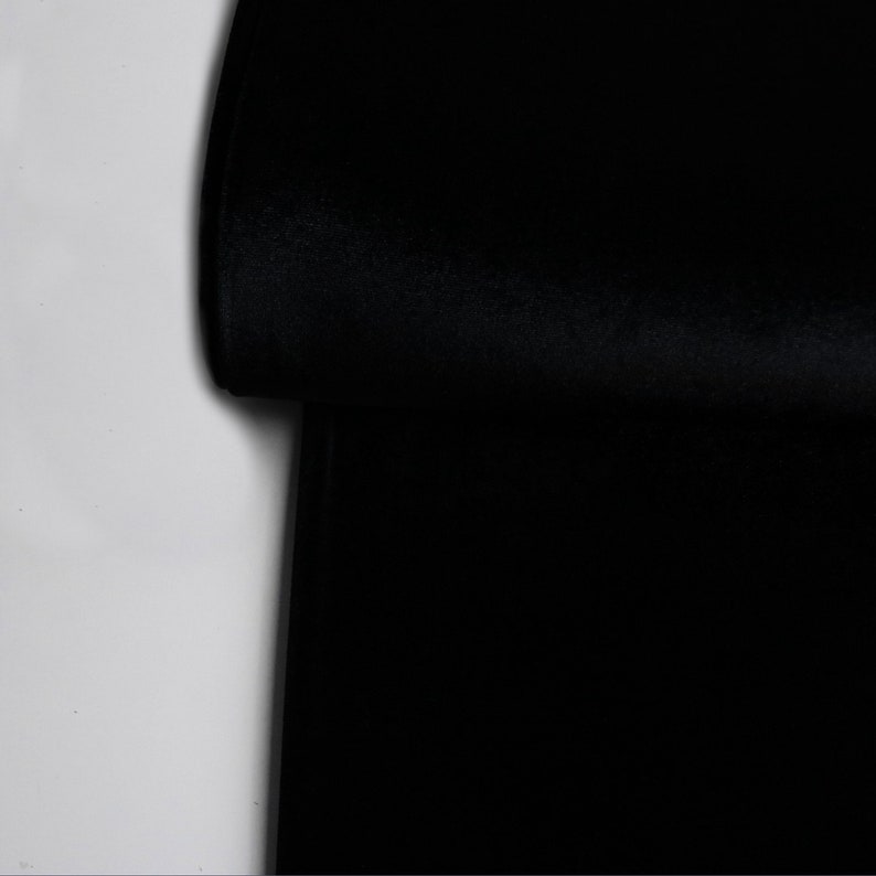 Pu&ograve; includere: Un primo piano di un tessuto nero piegato a met&agrave;. Il tessuto ha una texture liscia e vellutata.