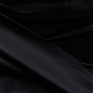 Pu&ograve; includere: Primo piano di un tessuto nero con una trama testurizzata. Il tessuto &egrave; piegato a met&agrave;, creando una linea diagonale.