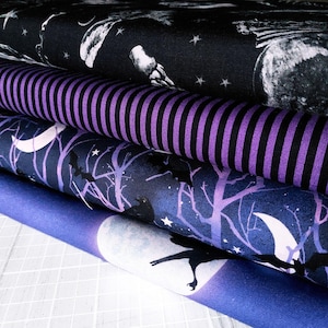 May include: A pile of patterned fabrics. The top fabric is black with a white raven and moon design. Beneath it is a purple and black striped fabric, followed by a dark blue fabric with a tree and raven design. The bottom layer is a blue fabric with a moon and raven.