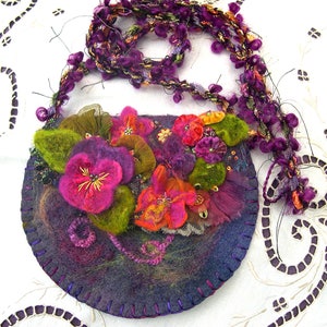 May include: A purple felt handbag with a beaded strap and floral embellishments. The bag is decorated with felt flowers in shades of pink, purple, green, and orange.