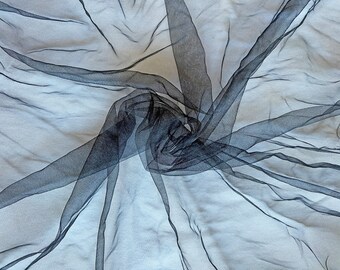 Peut inclure: Tissu noir transparent avec une texture douce et délicate. Le tissu est drapé et plié, créant un aspect fluide et aérien.