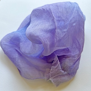 May include: A soft, crinkled, lavender-colored fabric. The fabric is sheer and has a delicate texture.