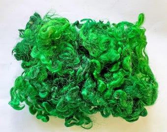 May include: Bright green curly fiber material, possibly wool or a synthetic blend, arranged in a dense, textured pile. The vibrant color and curly texture suggest it could be used for craft projects or decorative purposes.