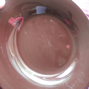 May include: A brown ceramic plate with a slightly raised rim. The plate has a glossy finish and shows signs of wear and tear.