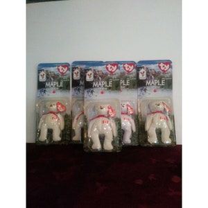 May include: Five white Ty Beanie Baby "Maple the Bear" plush toys in their original packaging. Each package features a red and white Canadian flag and the words "Maple the Bear".