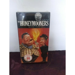 Puede incluir: Una cinta VHS de The Honeymooners, volumen 8 de 20, con el episodio "Funny Money - Trapped". La portada presenta una caricatura de Ralph Kramden y Ed Norton. La cinta es una edición limitada con una oferta de póster.