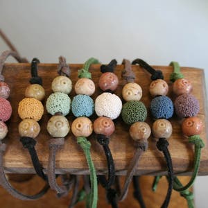 May include: Eight colorful beaded necklaces with brown leather cords. The beads are made of lava rock and have a variety of colors, including green, blue, red, and brown.