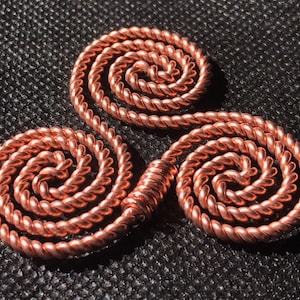 May include: A copper wire triquetra, a Celtic symbol of three interlocked spirals, is crafted with a twisted wire design. The triquetra is a popular symbol of life, unity, and eternity.