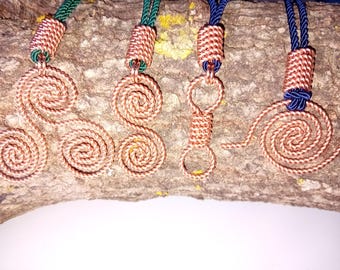 May include: Four copper wire pendants featuring intricate spiral and circular designs. Each pendant is secured with a woven copper wire bail and attached to a thick cord in either green or dark blue, showcasing metallic textures and patterns.