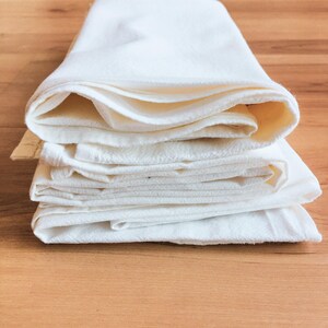 A stack of white folded towels on a wooden surface.