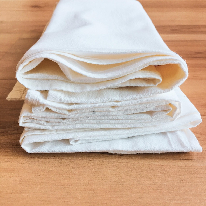 A stack of white folded towels on a wooden surface.