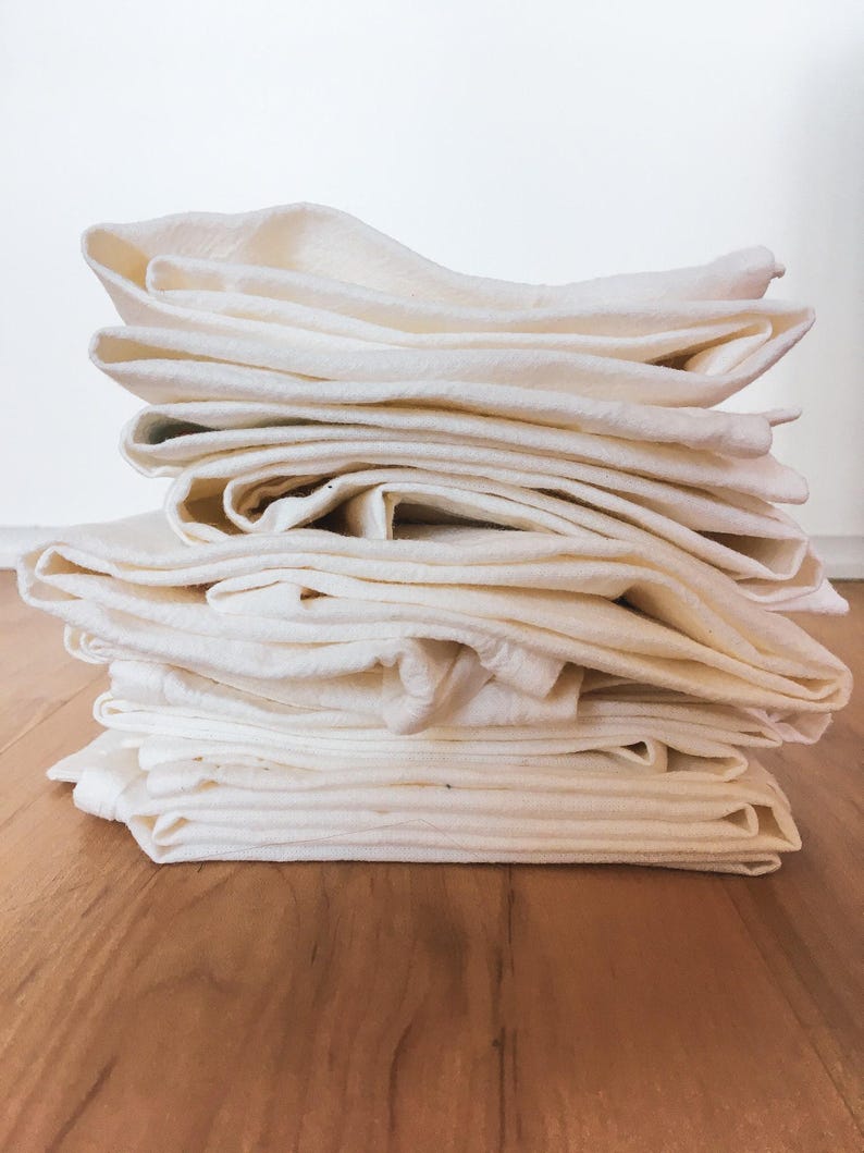 A stack of white towels or linens is neatly arranged on a wooden floor.