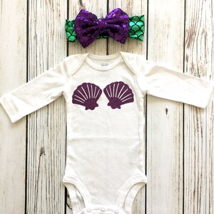 Peut inclure: Combinaison blanche pour b&eacute;b&eacute; avec des coquillages paillet&eacute;s violets sur le devant. Un bandeau &agrave; sequins vert et violet avec un n&oelig;ud est inclus.