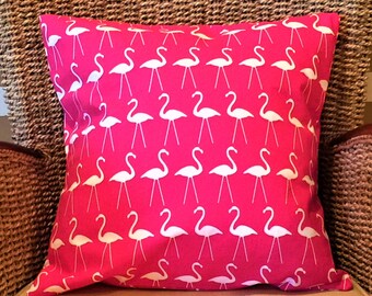 May include: A square decorative pillow with a vibrant pink background and a repeating pattern of white flamingo illustrations. The pillow is made of fabric and is designed for home decor.