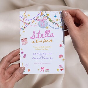 Puede incluir: Una invitaci&oacute;n azul claro con el texto "Stella is two fancy" en rosa y naranja. La invitaci&oacute;n incluye la fecha, hora y lugar de la fiesta, junto con elementos decorativos como una bola de discoteca e ilustraciones de pasteles.
