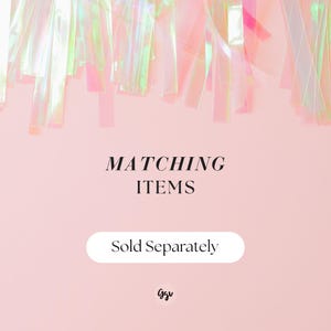 Puede incluir: Un fondo rosa con serpentinas iridiscentes en la parte superior. El texto "MATCHING ITEMS" est&aacute; en el centro, con "Sold Separately" debajo. Una firma est&aacute; en la parte inferior.