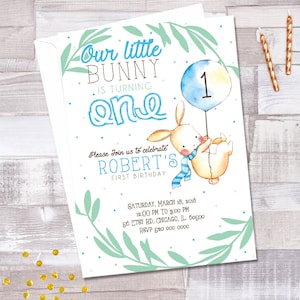 May include: A blue and white bunny holding a blue balloon with the number "1" on it. The text "Our little bunny is turning one" is at the top of the invitation. The text "Please join us to celebrate Robert's first birthday" is below the bunny. The invitation also includes the date, time, and location of the party.