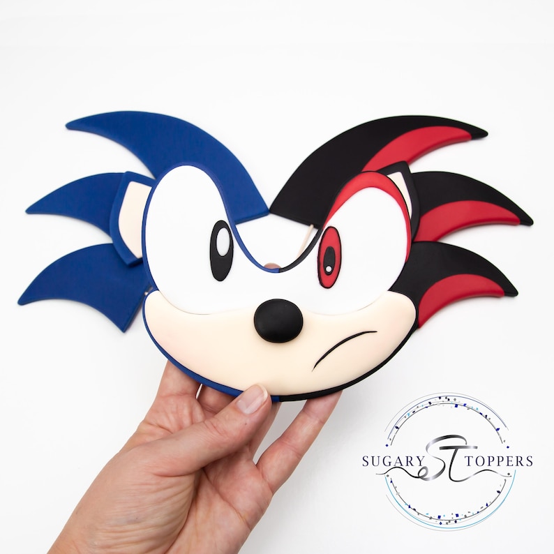 May include: A two-sided character face, featuring blue and black quills, white face, and red eyes. The character has a stern expression. The logo "Sugary Toppers" is visible in the bottom right corner.