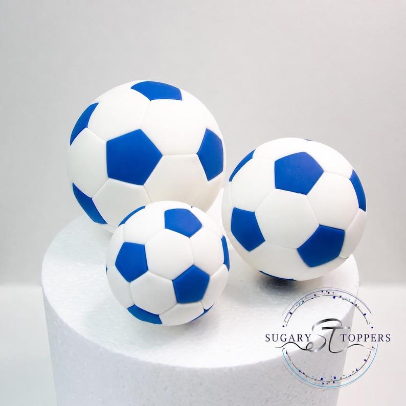 Pu&ograve; includere: Tre decorazioni sferiche per torte a forma di pallone da calcio con un classico motivo a pentagoni bianchi e blu. Il set comprende un pallone grande, uno medio e uno piccolo. &Egrave; visibile un logo circolare con il testo SUGARY TOPPERS.