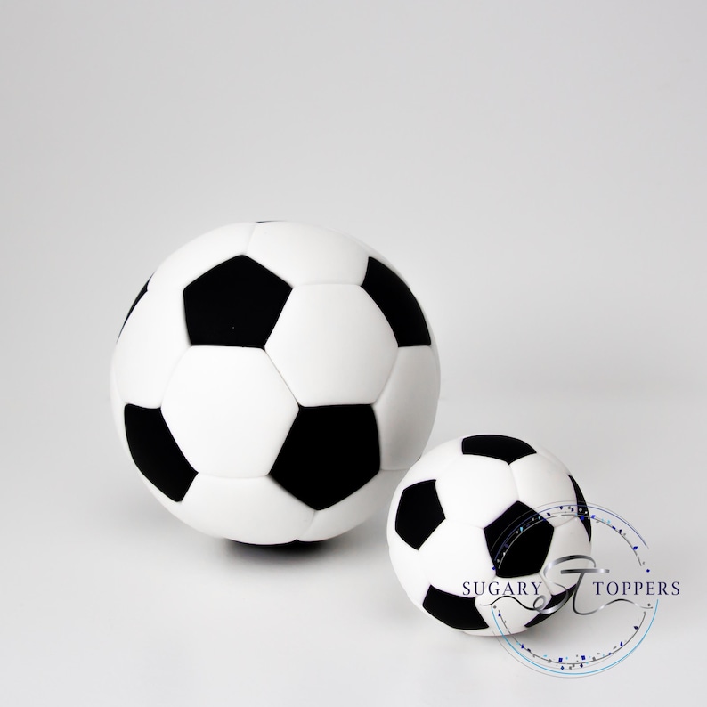 Pu&ograve; includere: Due decorazioni sferiche a forma di pallone da calcio con il classico motivo nero e bianco a pentagoni ed esagoni. Il pallone pi&ugrave; grande &egrave; posizionato a sinistra, mentre quello pi&ugrave; piccolo &egrave; a destra e riporta la scritta Sugary Toppers.