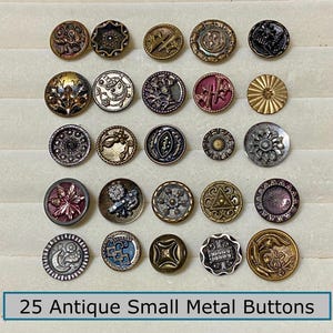 May include: A collection of 25 antique small metal buttons arranged in a grid. The buttons feature various circular designs, metallic finishes in gold, silver, bronze, and dark tones, and intricate embossed patterns. Text at the bottom reads 25 Antique Small Metal Buttons.