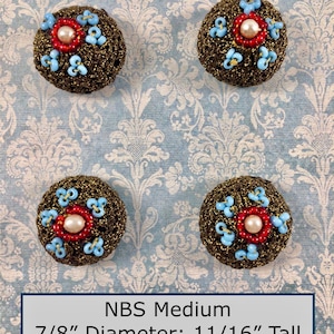 May include: Four round buttons with a metallic bronze crocheted surface, each featuring a central cream-coloured pearl bead surrounded by a ring of red seed beads and light blue bead clusters. Each button measures 2.22 cm in diameter and 1.75 cm tall.