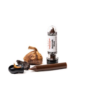 Puede incluir: Un cray&oacute;n de comida marr&oacute;n en un tubo transparente con una etiqueta en blanco y negro que dice "Food Crayon Black Garlic Ail Noir". Hay dos dientes de ajo negro al lado del cray&oacute;n.