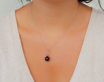 Peut inclure: Un collier en chaîne argent avec un pendentif en pierre noire.