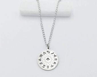 May include: Silver necklace with a round pendant featuring the zodiac signs and a star in the center.