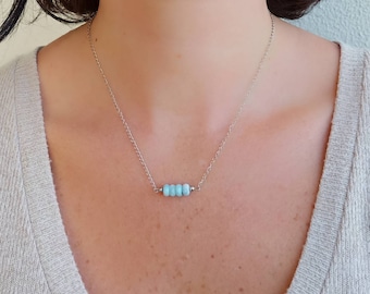 May include: A silver chain necklace with a light blue gemstone bar pendant.