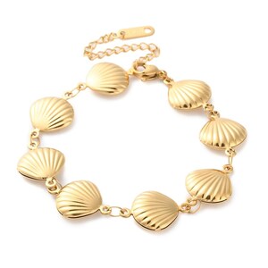 Op de afbeelding: Een goudkleurige armband met schelpenbedels. De armband heeft een fijne ketting en een karabijnsluiting. De schelpenbedels zijn gedetailleerd met geribbelde texturen, wat een accessoire in kust- of strandthema creëert. Ongeveer 18 cm lang.