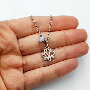Peut inclure: Un collier en chaîne argent avec un pendentif en forme de fleur de lotus argenté et une perle bleu clair.