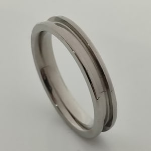 May include: A silver ring with a grooved design. The ring is made of metal and has a polished finish.