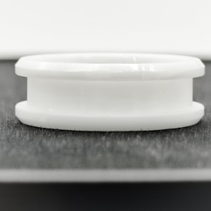 May include: White plastic ring with a beveled edge. The ring is smooth and has a glossy finish.