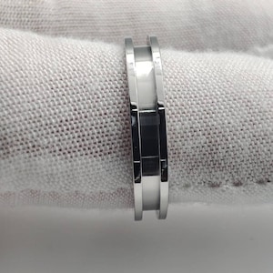May include: A silver ring with a grooved design. The ring is made of metal and has a polished finish.