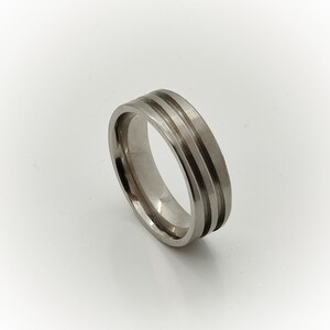 May include: A silver ring with two grooves around the band.