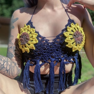 May include: A navy blue crochet top with sunflower details and fringe trim. The top is made of a soft, lightweight material and has a relaxed fit.