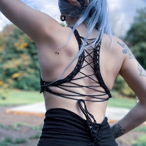 May include: A black crochet top with a criss-cross back design. The top is tied at the back with a long string.