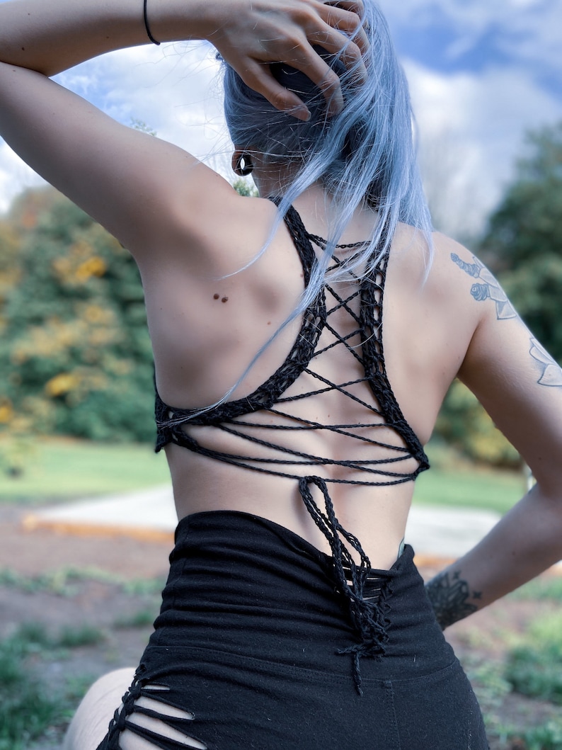 May include: A black crochet top with a criss-cross back design. The top is tied at the back with a long string.