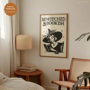 Puede incluir: Una ilustraci&oacute;n en blanco y negro de una bruja leyendo un libro con el texto "Bewitched & Bookish". La bruja lleva un sombrero negro con un dise&ntilde;o floral y un vestido negro. La ilustraci&oacute;n est&aacute; enmarcada en un marco marr&oacute;n claro.