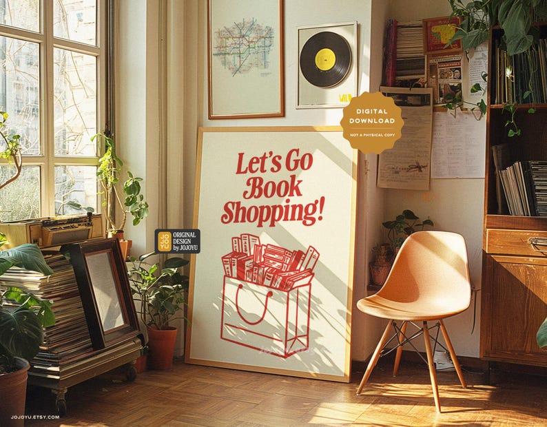 May include: A white poster with red text that says "Let's Go Book Shopping!"  The poster features a brown paper bag with a handle and a stack of books inside. The poster is hanging on a wall in a room with a wooden bookshelf and a chair.