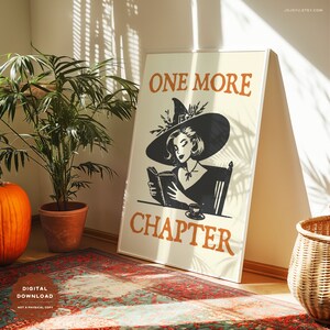 May include: A printable digital download of a poster featuring a witch reading a book with the text "One More Chapter". The poster has a cream background with orange and black text.