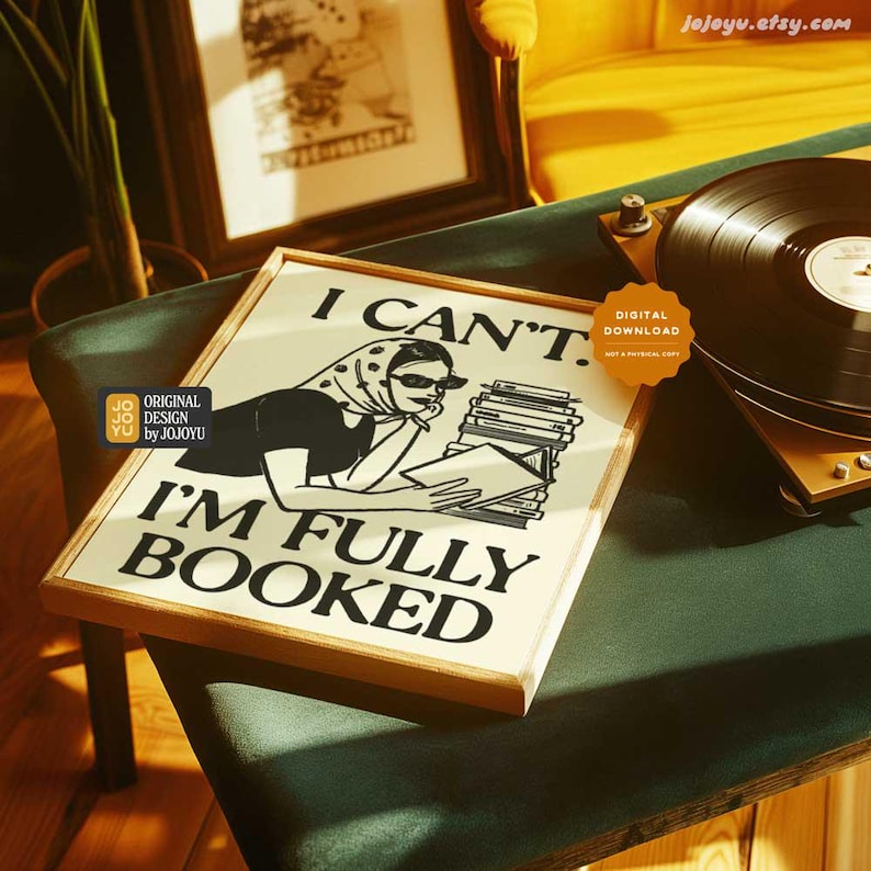 Op de afbeelding: Een ingelijst afdruk met een zwart-witte illustratie van een vrouw die een stapel boeken leest. De tekst op de afdruk luidt "Ik kan niet. Ik ben volgeboekt."