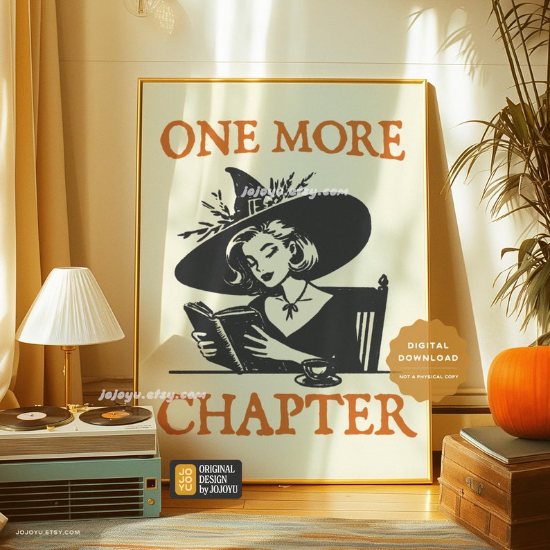 May include: A digital download print featuring a witch reading a book with the text "One More Chapter" in orange and black. The witch is wearing a black hat and dress and is sitting in a chair. The print is on a white background with a gold frame.