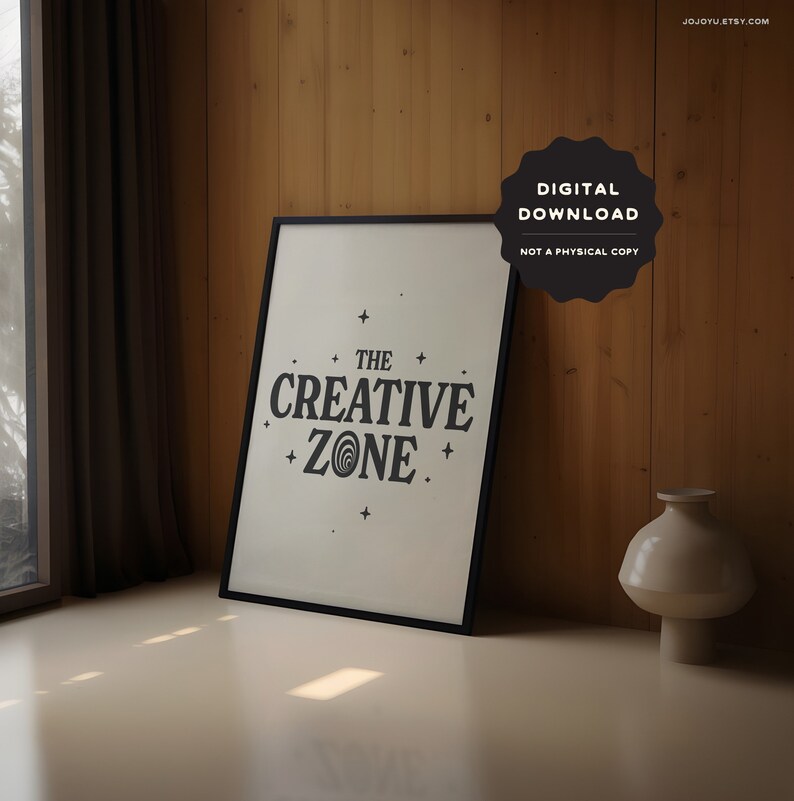 May include: A black framed print with a white background and black text that reads "The Creative Zone" with a stylized swirl design in the word "Zone". The print is on a wooden surface with a vase next to it.