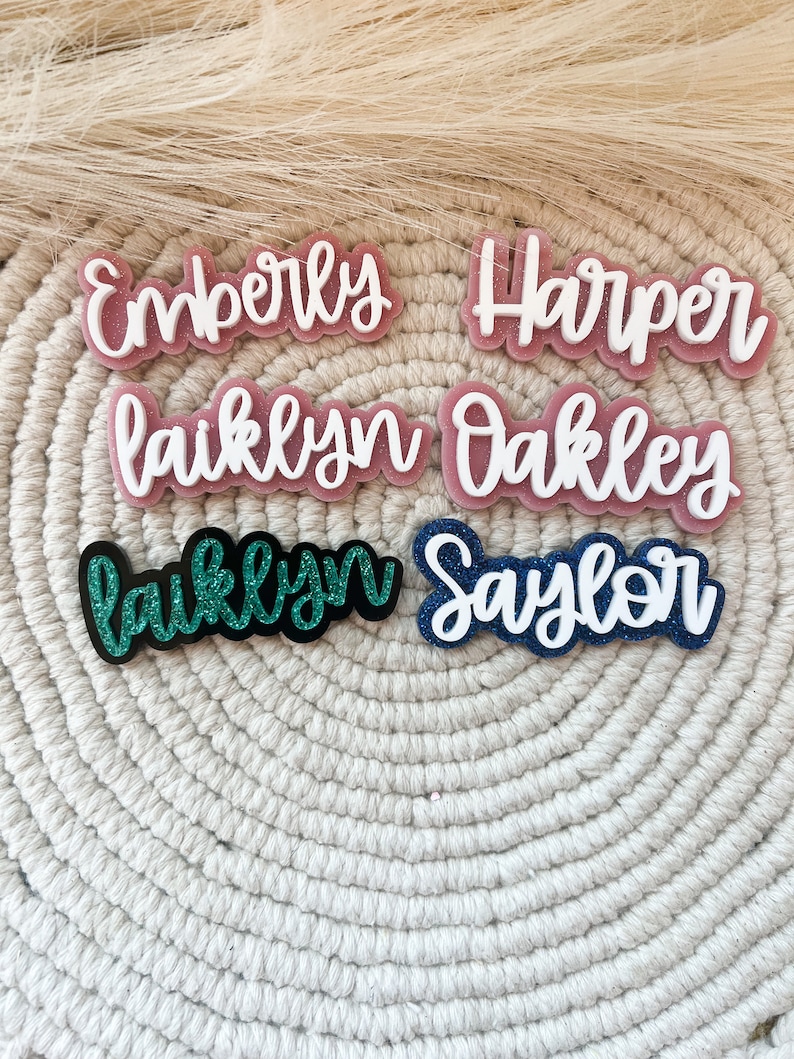 Pu&ograve; includere: Sei targhe con nome personalizzate con accenti glitter. I nomi sono "Emberly", "Harper", "Laiklyn", "Oakley", "Laiklyn" e "Saylor".