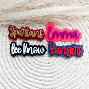 Pu&ograve; includere: Quattro targhette con nome in acrilico con dettagli glitter. I nomi sono "Spartans", "Emma", "Lee Know" e "Rangers".
