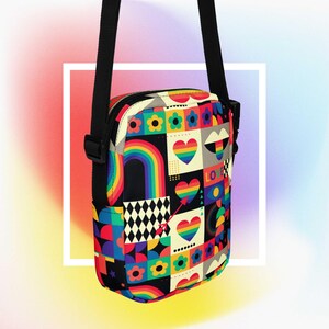 May include: A crossbody bag with a black strap, featuring a vibrant patchwork design. The bag showcases rainbows, hearts, flowers, and geometric patterns in multiple colours. The word "LOVE" is displayed on the bag.
