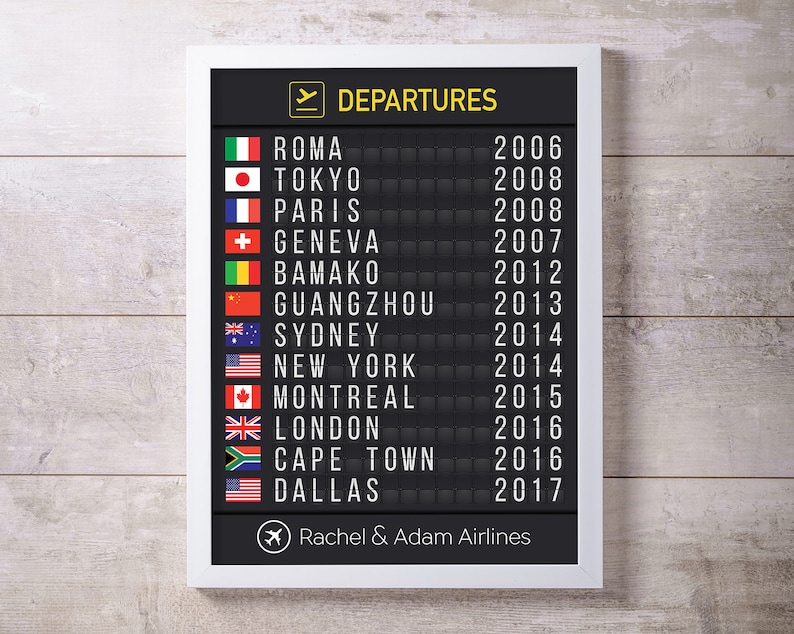 Puede incluir: Un tablero de salidas de aeropuerto en blanco y negro con un marco blanco. El tablero muestra una lista de ciudades y a&ntilde;os, incluyendo Roma, Tokio, Par&iacute;s, Ginebra, Bamako, Guangzhou, Sydney, Nueva York, Montreal, Londres, Ciudad del Cabo y Dallas. El tablero tambi&eacute;n incluye un peque&ntilde;o icono de avi&oacute;n y el texto "Rachel & Adam Airlines".