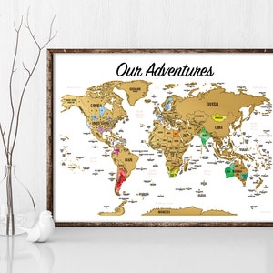 May include: A gold world map with a white background and the text "Our Adventures" at the top. The map is divided into countries and continents, with each country labeled in black text. The map is framed in a brown wooden frame.